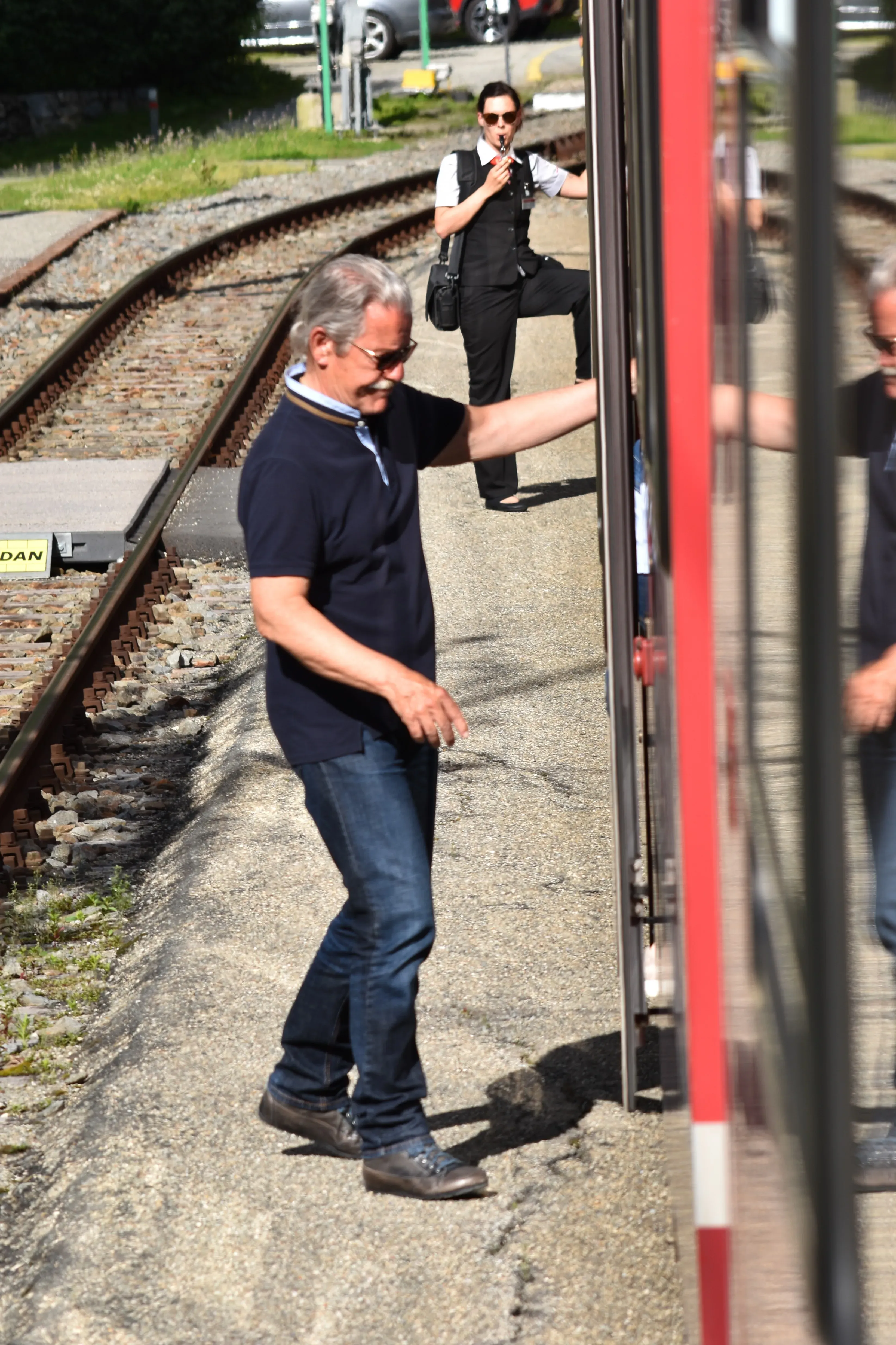 Man climbing aboard a RhB train at Brusio Station, Switzerland.