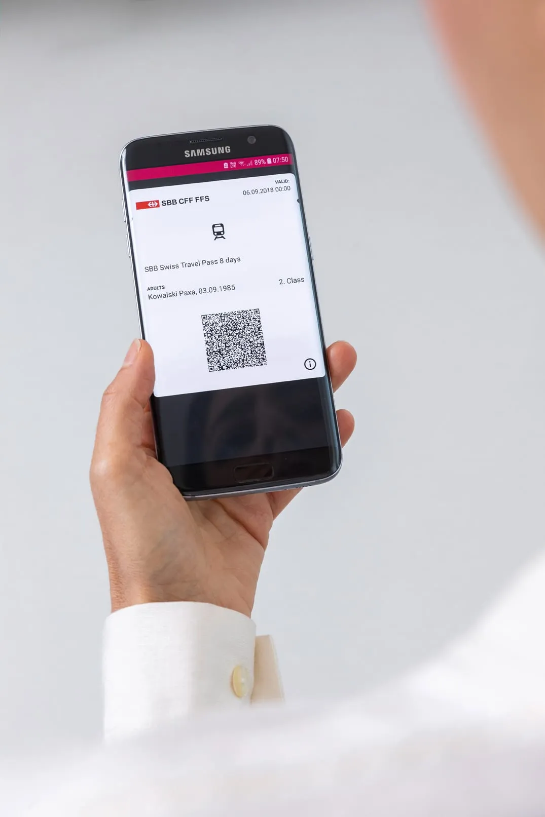 A hand holding a smartphone with a digital Swiss Travel Pass displayed on the screen.